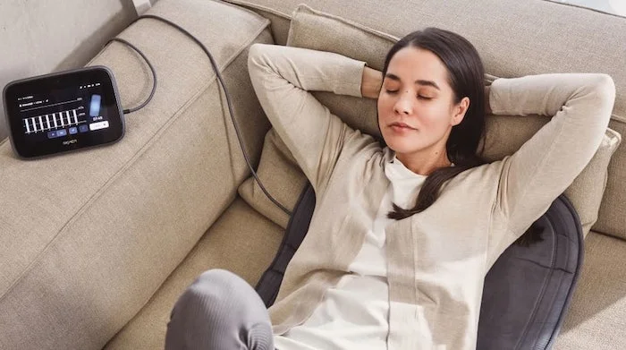 Eine Frau entspannt auf dem Sofa während einer Anwendung mit dem BEMER evo System.