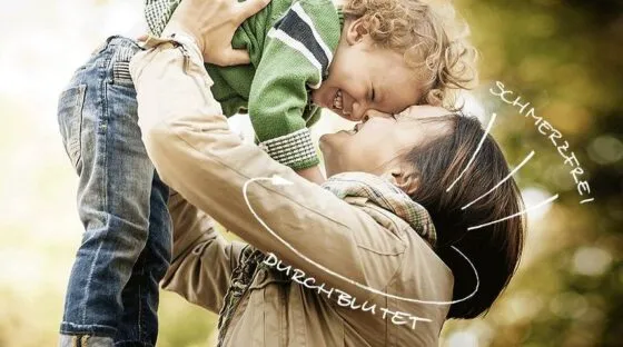 Eine Frau hebt lachend ein Kind hoch, beide berühren sich mit den Stirnen, Szene voller Nähe.