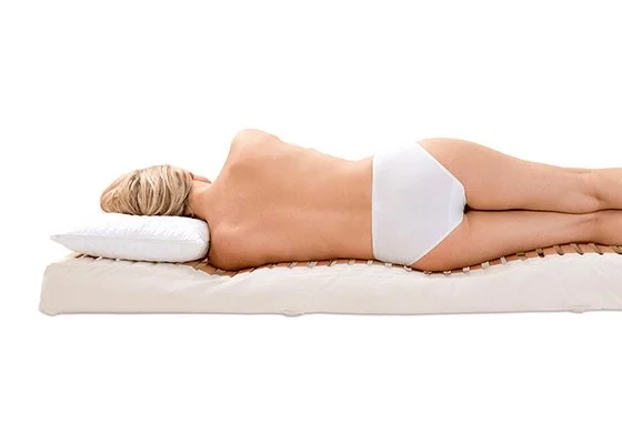Eine Frau liegt seitlich auf einer Ergofit Matratze mit ergonomischer Unterstützung der Wirbelsäule.