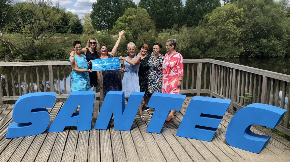 Mitarbeiterinnen von Santec stehen gemeinsam im Freien hinter großen Buchstaben „SANTEC“.